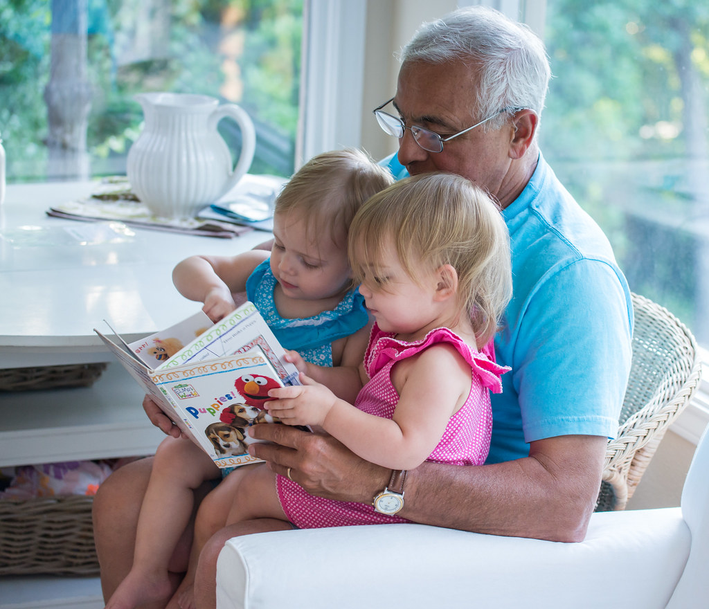 A grandparent reading with two small children at home